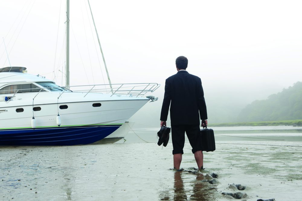 Executive walking in mud towards boat for sale