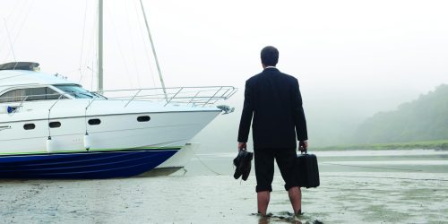 Executive walking in mud towards boat for sale